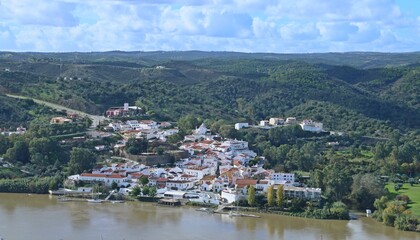 Fototapeta na wymiar Alcoutim, pequeño pueblo en la región del Algarve, Portugal, frontera con España. Vista de su puerto deportivo y casas a orillas del río Guadiana desde en Sanlúcar de Guadiana en el lado español.