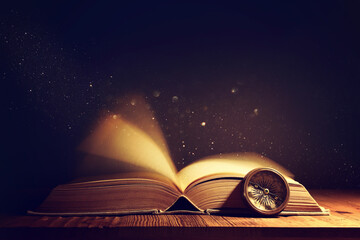 image of open antique book on wooden table with glitter overlay © tomertu