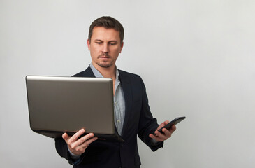 Young businessman using laptop and phone on white background