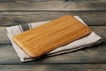 Wooden board with kitchen napkin on dark wooden table