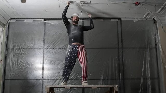 Happy american builder in hardhat is dancing. Funny working movements on the background of a construction site. slow motion.