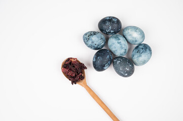Easter eggs handmade painted by hibiscus tea on white background. Wooden spoon with Hibiscus tea leaves.Easter tradition
