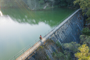Single Hiker standing on a dam of reservoir - Powered by Adobe