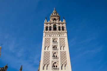 Monument of the giralda of seville in the gothic cathedral. It can be seen rising into the blue sky of the city. It is the largest religious building in the world. Tourism and travel concept.