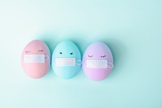 Three colorful Easter eggs with painted eyes and with protective mask covid-19. Happy Easter holidays. The concept of celebrating Easter in conditions of self-isolation and quarantine