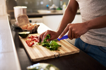 Make sure your meals has enough veggies. Cropped shot of an unrecognizable man chopping vegetables while making a meal in his kitchen at home.