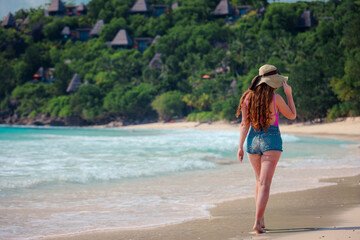 Fototapeta na wymiar A girl in a hat on a beautiful paradise beach