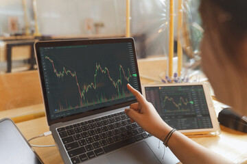 Businesswoman, female trader, investor pointing, using laptop, tablet with graph chart for stock market, Bitcoin cryptocurrency trading, strategy planning on money investing on online trading platform - 496061755