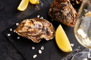 Fresh closed oysters with lemon on slate plate - 496061798