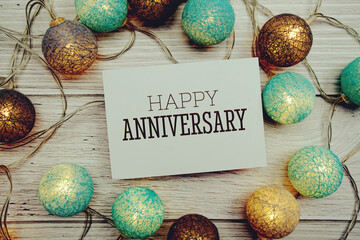 Happy Anniversary text on paper card with LED Cotton ball Decoration on wooden background