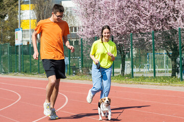 Young happy couple running with a dog