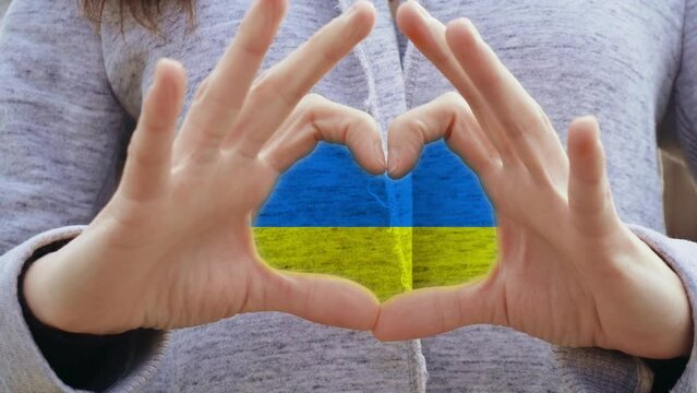 Ukraine flag in center of arms in shape of heart in support of country defense and condemns military invasion. Concept of partnerships and allied countries and nations