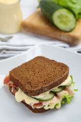 Delicious sandwich with vegetables, ham and mayonnaise on plate