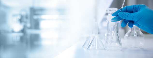 hand of scientist with test tube and flask in medical chemistry lab banner background