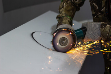 a worker cuts a circle in metal with an angle grinder 