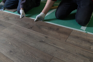 A worker hands knocking on a laminate connecting the panels with a Lock Click