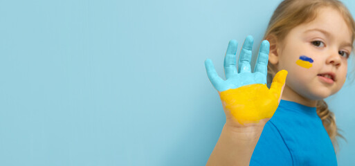 Yellow and blue paint on the hand of a little girl. Ukrainian flag symbols concept. Copy space