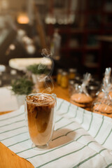 Ice coffee on table with cream being poured into it showing the texture and refreshing look of the drink