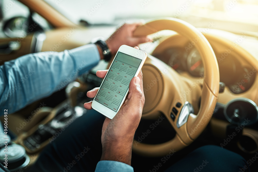 Poster Doing a quick check in with his schedule. Closeup shot of an unrecognisable businessman using a cellphone while driving.