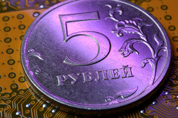 A coin with a face value of 5 rubles lies on a microcircuit. close-up. Translation of the inscription on the coin: 