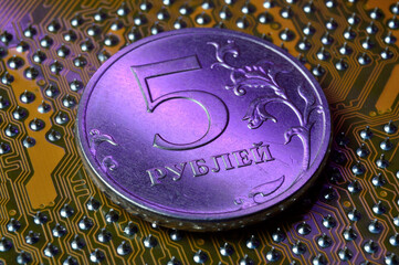 A coin with a face value of 5 rubles lies on a microcircuit. close-up. Translation of the inscription on the coin: 