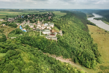 Obraz premium An amazing aerial view of the old St. John the Theologian Monastery in the village of Khreshchatyk, Ternopil region, on a steep hillside with a forest, the Dniester River flows below. Dniester Canyon