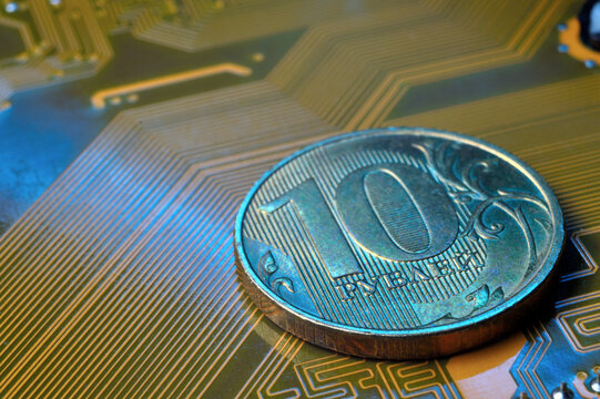 A coin with a face value of 10 rubles lies on a microcircuit. close-up. Translation of the inscription on the coin: "10 rubles" The concept of the digital economy in the Russian Federation