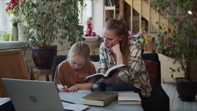 A woman checks her homework with her daughter. Mom gives advice and tells what to fix