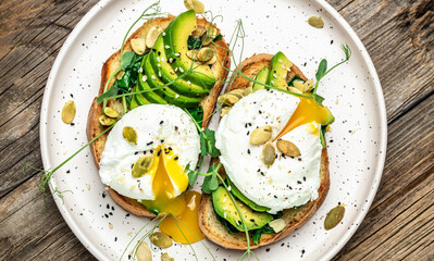 Poached egg on bread with spinach, avocado and pumpkin seeds on the wooden table, Healthy food, keto diet, diet lunch concept. Top view