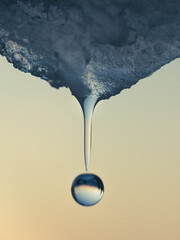 A drop of water falling from the melting ice at sunset