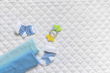 For a newborn, socks, blue diapers, a teether, lace on a white textured background. Copy space.