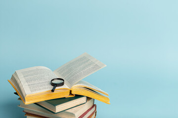 Vintage book and magnifying glass on light blue background. Education background. Literacy day. World books day. Copy space