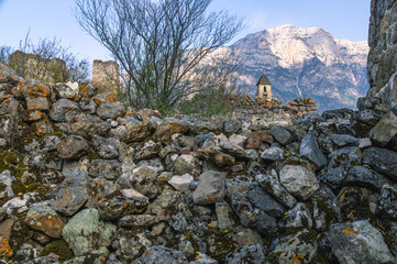 A pile of stones of the destroyed wall of an ancient structure. An old medieval tower for watching enemies against the background of mountains.