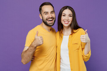 Fototapeta premium Young cheerful happy fun couple two friends family man woman together in yellow casual clothes looking camera showing thumb up like gesture cuddle isolated on plain violet background studio portrait.