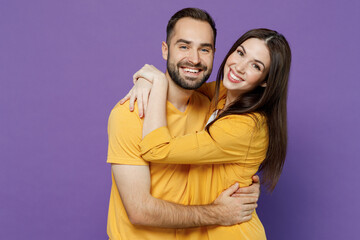 Young smiling happy nice lovely cheerful couple two friends family man woman 20s together wearing yellow casual clothes looking camera hud cuddle isolated on plain violet background studio portrait