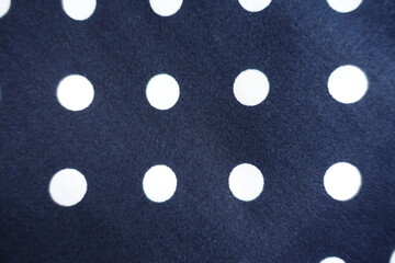 Swatch of dark blue cotton fabric with white polka dot pattern