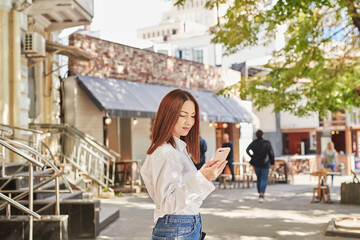 Young beautiful woman walks in city. Portrait of girl on street. hands with phone. Online work, distance learning.
