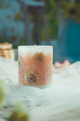 Handmade candles of a unique design, with different flowers, dry leaves on a light background. Candles made from organic wax, paraffin wax. Relaxation atmosphere. Luxurious lifestyle.