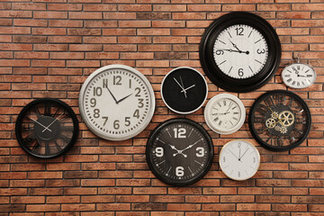 Collection of clocks hanging on red brick wall