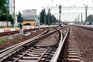 Fototapeta na wymiar Railway station with rails, buildings and trains in the distance