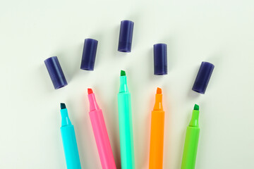 Many colorful markers on beige background, flat lay. School stationery