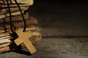 Wooden Christian cross and old books on table, closeup. Space for text