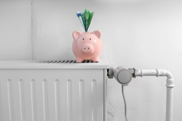heating, energy crisis and consumption concept - piggy bank with money on radiator at home