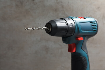 Modern electric power drill near light grey wall, closeup