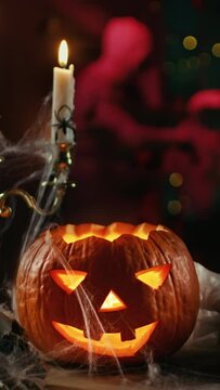 Halloween Still Life Colorful Theme: Scary Decorated Dark Room with Burning Pumpkin Head with Candlestick Inside. Background: Silhouette of Monster Walking. Vertical Screen Orientation Video