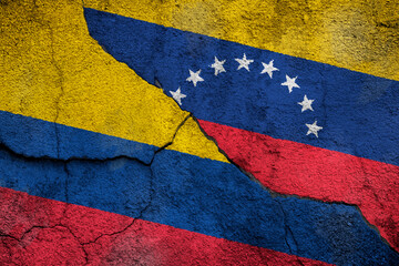 Full frame photo of weathered flags of Colombia and Venezuela painted on a cracked wall. 2021 Apure...