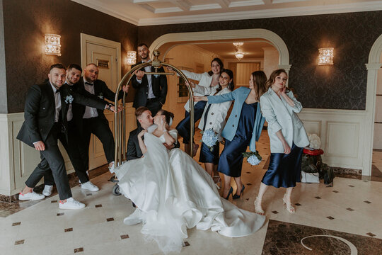 Joyful moment on the wedding of the young couple. Cheerful and fun groom with bride, bridesmaids and groomsmen posing in hotel