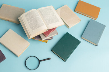 Vintage books and magnifying glass on light blue background. Education background. World books day. Literacy day