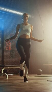 Fit Athletic Blond Woman Exercises with Jumping Rope in a Loft Style Gym. She Does Her Intense Cross Fitness Training Program. Vertical Screen Orientation Video