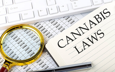 CANNABIS LAWS text on notebook with chart, magnifier,keyboard and pen